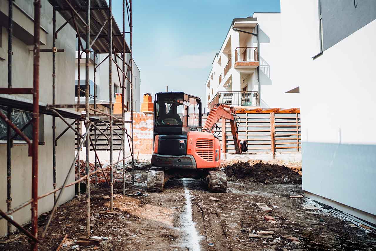 Excavator in a narrow passage beside scaffolding